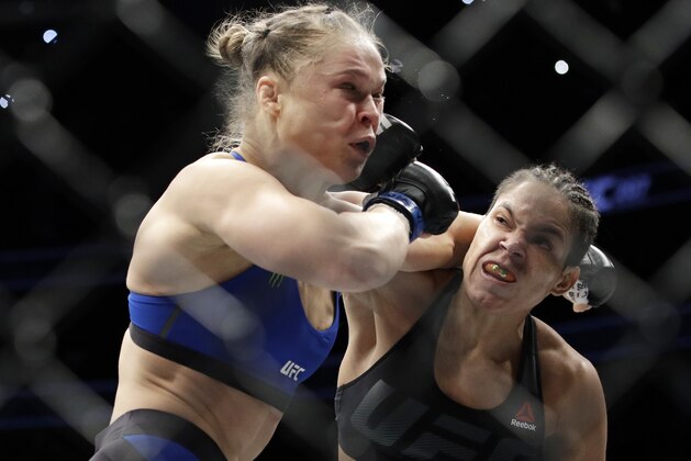 Amanda Nunes, right, connects with Ronda Rousey during the first round of their women's bantamweight championship mixed martial arts bout at UFC 207, Friday, Dec. 30, 2016, in Las Vegas. Nunes won the fight after it was stopped in the first round. (AP Photo/John Locher)