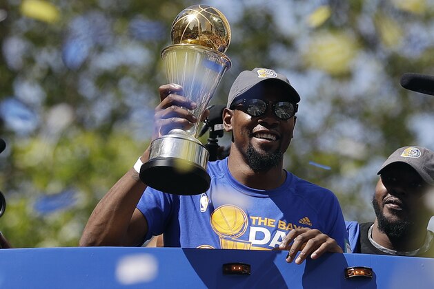 Golden State Warriors' Kevin Durant smiles as he holds the NBA Finals MVP trophy during a parade and rally after winning the NBA basketball championship Thursday, June 15, 2017, in Oakland, Calif. (AP Photo/Marcio Jose Sanchez)