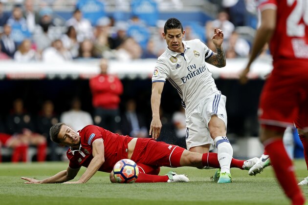 Real Madrid's James Rodriguez, right, battles for the ball with Sevilla's Clement Lenglet during the La Liga soccer match between Real Madrid and Sevilla at the Santiago Bernabeu stadium in Madrid, Sunday, May 14, 2017. (AP Photo/Francisco Seco)
