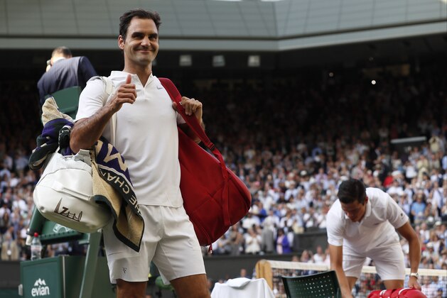 Switzerland's Roger Federer, left, celebrates as he leaves the court after beating Canada's Milos Raonic, right, at the end of their Men's Singles Quarterfinal Match on day nine at the Wimbledon Tennis Championships in London Wednesday, July 12, 2017. (AP Photo/Kirsty Wigglesworth)