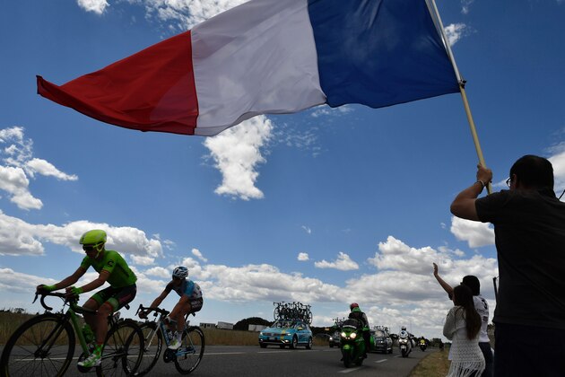 Netherlands' Tom Slagter (L) and France's Cyril Gautier(R) pursue the head of the pack as a man waves a French national flag during the 178 km twelvelth stage of the 103rd edition of the Tour de France cycling race on July 14, 2016 between Montpellier and Chalet Reynard. / AFP / jeff pachoud        (Photo credit should read JEFF PACHOUD/AFP/Getty Images)