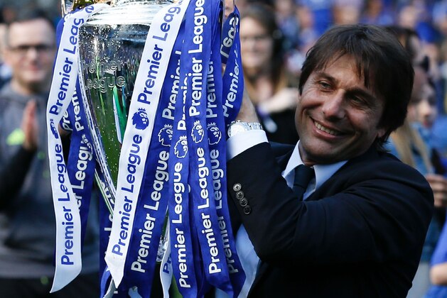 Chelsea's Italian head coach Antonio Conte raises the English Premier League trophy, as players celebrate their league title win at the end of the Premier League football match between Chelsea and Sunderland at Stamford Bridge in London on May 21, 2017.
Chelsea's extended victory parade reached a climax with the trophy presentation on May 21, 2017 after being crowned Premier League champions with two games to go.  / AFP PHOTO / Ian KINGTON / RESTRICTED TO EDITORIAL USE. No use with unauthorized audio, video, data, fixture lists, club/league logos or 'live' services. Online in-match use limited to 75 images, no video emulation. No use in betting, games or single club/league/player publications.  /         (Photo credit should read IAN KINGTON/AFP/Getty Images)