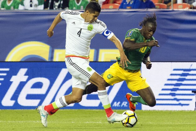 Hugo Ayala (4) of Mexico trips Darren Mattocks (10) of Jamaica as they fight for control of the ball during the Mexico vs Jamaica CONCACAF Group C Gold Cup soccer game on July 13, 2017 at Sports Authority Field at Mile High in Denver, Colorado.  / AFP PHOTO / Jason Connolly        (Photo credit should read JASON CONNOLLY/AFP/Getty Images)