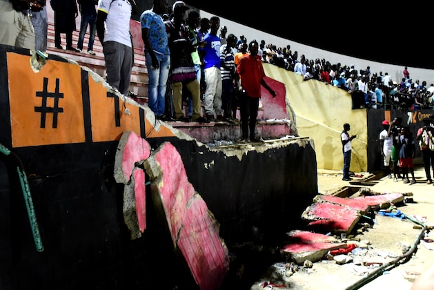 People stand before a collapsed wall at Demba Diop stadium July 15, 2017 in Dakar after a football game between local teams Ouakam and Stade de Mbour. 
Eight people were killed during Senegal's football league final in Dakar on Saturday in a stampede that broke out following clashes at the end of the match, the official APS news agency said. The wall collapse added many more to be injured.   / AFP PHOTO / SEYLLOU        (Photo credit should read SEYLLOU/AFP/Getty Images)