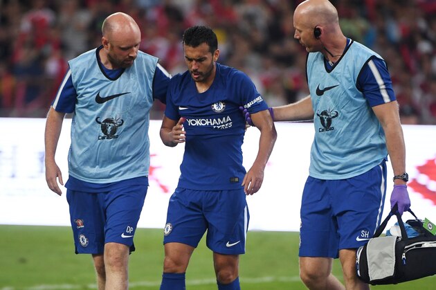Chelsea's Pedro (C) leaves the field after a collision with Arsenal's David Ospina during their pre-season football match in Beijing's National Stadium, known as the Bird's Nest, on July 22, 2017. / AFP PHOTO / GREG BAKER        (Photo credit should read GREG BAKER/AFP/Getty Images)