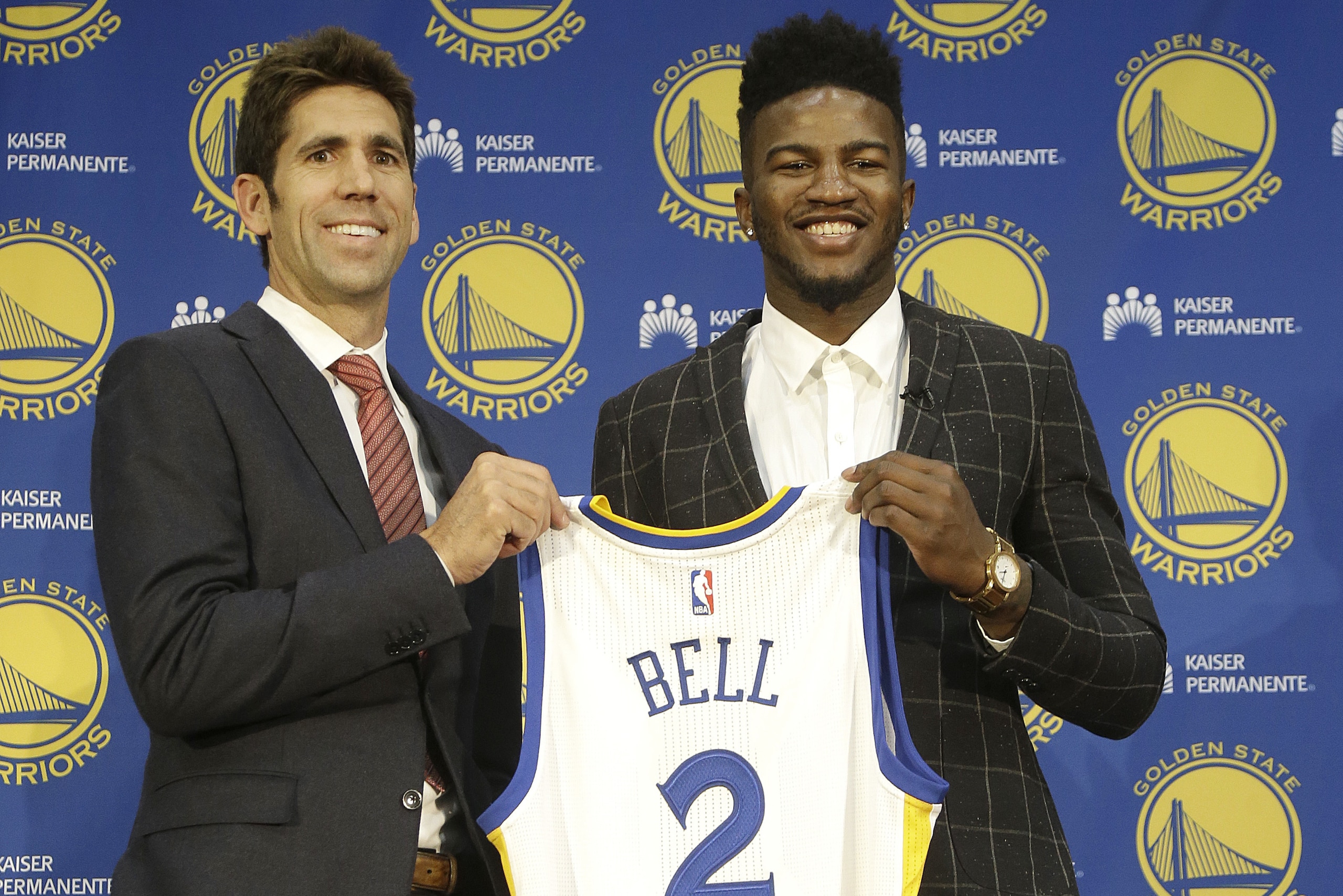 Golden State Warriors NBA basketball draft pick Jordan Bell, right, and general manager Bob Myers pose for photos with a jersey at a news conference in Oakland, Calif., Friday, June 23, 2017. (AP Photo/Jeff Chiu)