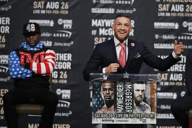 Floyd Mayweather Jr., background left, listens as Conor McGregor speaks during a news conference at Staples Center Tuesday, July 11, 2017, in Los Angeles. The two will fight in a boxing match in Las Vegas on Aug. 26. (AP Photo/Jae C. Hong)