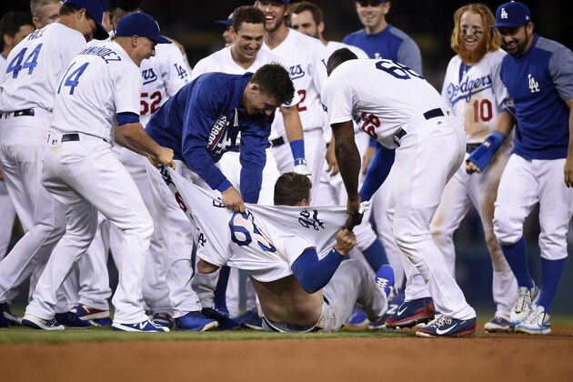 LOS ANGELES, CA - JULY 30: Kyle Farmer #65 of the Los Angeles Dodgers has his shirt ripped apart by teammates Enrique Hernandez #14 Cody Bellinger #35 and Yasiel Puig #66 after hitting the game win double making his Major League debut against the San Francisco Giants in the 11th inning at Dodger Stadium Stadium July 30, 2017, in Los Angeles, California. (Photo by Kevork Djansezian/Getty Images)
