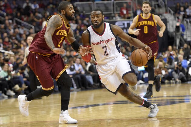 Washington Wizards guard John Wall, right, dribbles against Cleveland Cavaliers guard Kyrie Irving, left, during the second half of an NBA basketball game, Friday, Nov. 11, 2016, in Washington. At rear is Cavaliers forward Kevin Love (0). The Cavaliers won 105-94. (AP Photo/Nick Wass)