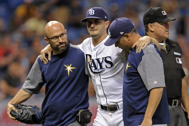 A Tampa Bay Rays trainer and manager Kevin Cash, right, help pitcher Jake Odorizzi, center, off the field after he was hit by a line drive on his right leg from Boston Red Sox's Eduardo Nunez during the fifth inning of a baseball game Wednesday, Aug. 9, 2017, in St. Petersburg, Fla. (AP Photo/Steve Nesius)