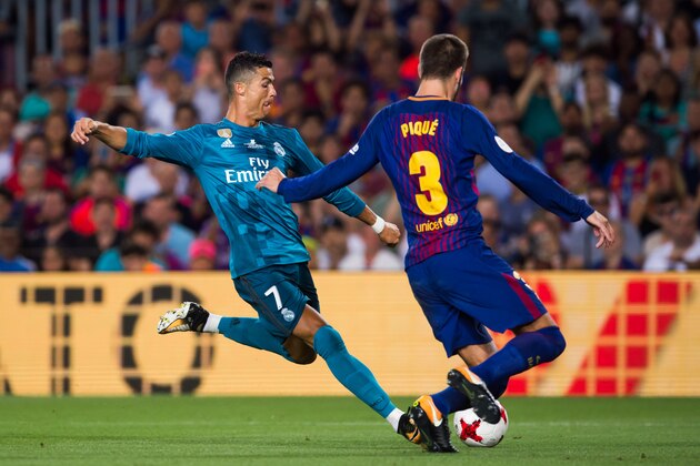 BARCELONA, SPAIN - AUGUST 13:  Cristiano Ronaldo of Real Madrid CF shoots the ball under pressure from Gerard Pique of FC Barcelona during the Supercopa de Espana Supercopa Final 1st Leg match between FC Barcelona and Real Madrid at Camp Nou on August 13, 2017 in Barcelona, Spain.  (Photo by Alex Caparros/Getty Images)