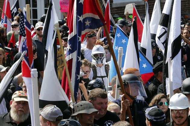 FILE- In this Saturday, Aug. 12, 2017, photo white nationalist demonstrators walk into the entrance of Lee Park surrounded by counter demonstrators in Charlottesville, Va. The Detroit Lions said Tuesday, Aug. 15, that they “detest and disavow” any use of their logo associated with the event Saturday in Charlottesville. A photo taken at the demonstration showed someone with a logo similar to the one the Lions use, although it was blue and red and had stars on it. (AP Photo/Steve Helber, File)