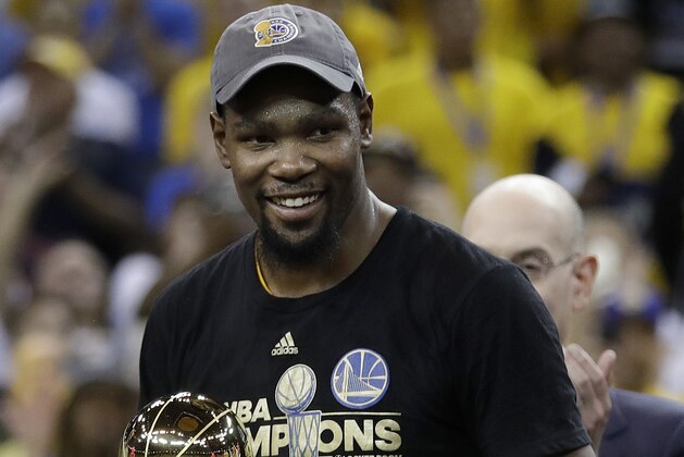Golden State Warriors forward Kevin Durant smiles as he holds the Bill Russell NBA Finals Most Valuable Player Award after Game 5 of basketball's NBA Finals between the Warriors and the Cleveland Cavaliers in Oakland, Calif., Monday, June 12, 2017. The Warriors won 129-120 to win the NBA championship. (AP Photo/Marcio Jose Sanchez)