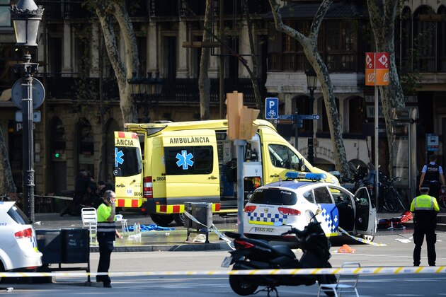 A policemen and a medical staff member stand past police cars and an ambulance in a cordoned off area after a van ploughed into the crowd, injuring several persons on the Rambla in Barcelona on August 17, 2017. / AFP PHOTO / Josep LAGO        (Photo credit should read JOSEP LAGO/AFP/Getty Images)