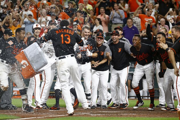 Teammates greet Baltimore Orioles' Manny Machado (13) as he approaches home plate after hitting a game-winning grand slam in the ninth inning of a baseball game against the Los Angeles Angels in Baltimore, Friday, Aug. 18, 2017. Baltimore won 9-7. (AP Photo/Patrick Semansky)