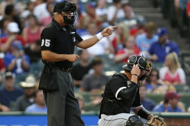 Home plate umpire Tim Timmons (left) signals while Chicago White Sox catcher Kevan Smith, right, adjusts his mask during the first inning of a baseball game against the Chicago White Sox, Saturday Aug. 19, 2017, in Arlington, Texas. Umpires wore white wristbands during games Saturday, protesting