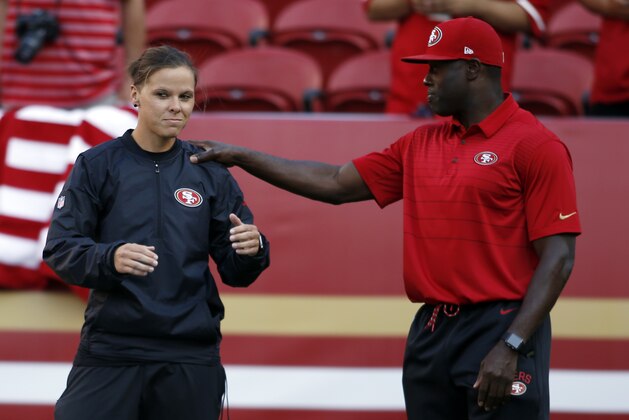 San Francisco 49ers assistant coach Katie Sowers, left, talks with a fellow coach before a preseason NFL football game against the Denver Broncos Saturday, Aug. 19, 2017, in Santa Clara, Calif. (AP Photo/D. Ross Cameron)