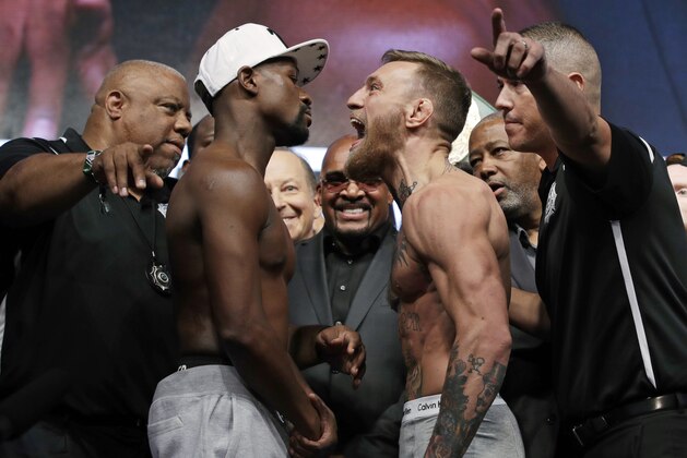 Floyd Mayweather Jr., center left, and Conor McGregor face off during a weigh-in Friday, Aug. 25, 2017, in Las Vegas. The two are scheduled to fight in a boxing match Saturday in Las Vegas. (AP Photo/John Locher)