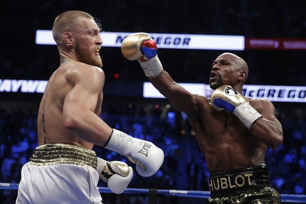 Floyd Mayweather Jr. hits Conor McGregor in a super welterweight boxing match Saturday, Aug. 26, 2017, in Las Vegas. (AP Photo/Isaac Brekken)