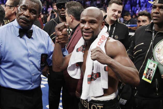 Floyd Mayweather Jr. poses for photographers after defeating Conor McGregor in a super welterweight boxing match Saturday, Aug. 26, 2017, in Las Vegas. (AP Photo/Isaac Brekken)