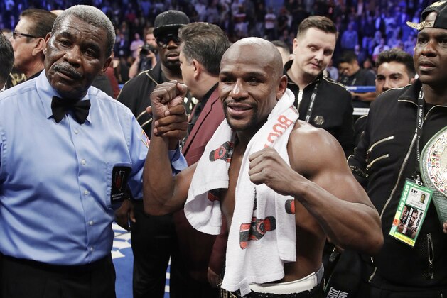 Floyd Mayweather Jr. poses for photographers after defeating Conor McGregor in a super welterweight boxing match Saturday, Aug. 26, 2017, in Las Vegas. (AP Photo/Isaac Brekken)