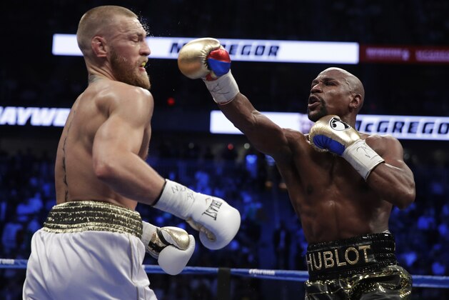 Floyd Mayweather Jr. hits Conor McGregor in a super welterweight boxing match Saturday, Aug. 26, 2017, in Las Vegas. (AP Photo/Isaac Brekken)