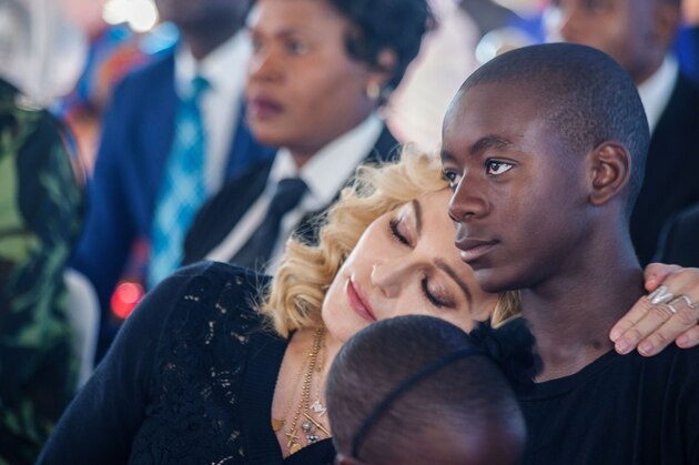 US pop star Madonna (L) rests her head on the shoulder of her adopted son David Banda during the opening ceremony of the Mercy James Children's Hospital at Queen Elizabeth Central Hospital in Blantyre, Malawi, on July 11, 2017.
Madonna on July 11 took her four adopted Malawian children back to their home country for the opening of a paediatric hospital wing that her charity has built. / AFP PHOTO / AMOS GUMULIRA        (Photo credit should read AMOS GUMULIRA/AFP/Getty Images)