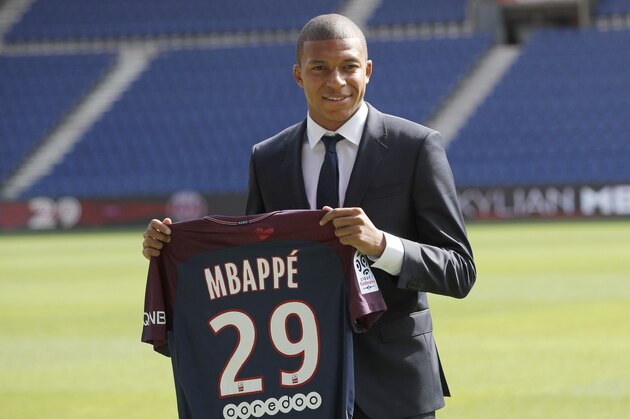 French soccer player Kylian Mbappe poses with his team shirt following a press conference in Paris, Wednesday, Sept. 6, 2017. Mbappe is a young man in a big hurry and wants to
