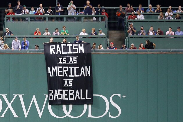 BOSTON, MA - SEPTEMBER 13: A banner with the message 'Racism is as American as baseball' is draped over the Green Monster during the fourth inning of the game between the Boston Red Sox and the Oakland Athletics at Fenway Park on September 13, 2017 in Boston, Massachusetts. (Photo by Maddie Meyer/Getty Images)