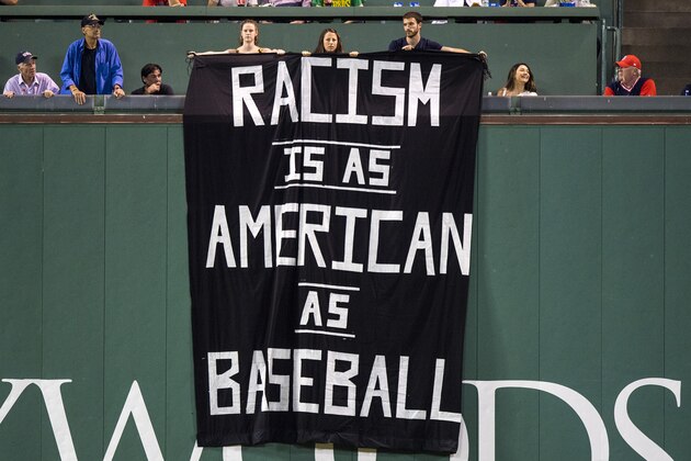 BOSTON, MA - SEPTEMBER 13: Fans display a sign that reads 'Racism is as American as Baseball' over the Green Monster during the fourth inning of a game between the Boston Red Sox and the Oakland Athletics on September 13, 2017 at Fenway Park in Boston, Massachusetts. (Photo by Billie Weiss/Boston Red Sox/Getty Images)