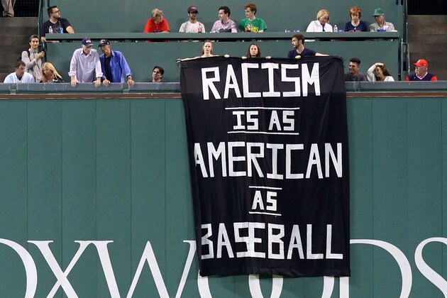 BOSTON, MA - SEPTEMBER 13: A banner with the message 'Racism is as American as baseball' is draped over the Green Monster during the fourth inning of the game between the Boston Red Sox and the Oakland Athletics at Fenway Park on September 13, 2017 in Boston, Massachusetts. (Photo by Maddie Meyer/Getty Images)