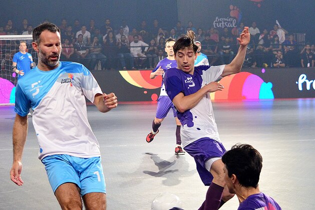 Former Manchester United footballer Ryan Giggs (L) is tackled while taking part in the final of the Indian Premier Futsal Football League match at The Peddem Indoor Stadium in Mapusa on July 24, 2016. / AFP / STR        (Photo credit should read STR/AFP/Getty Images)