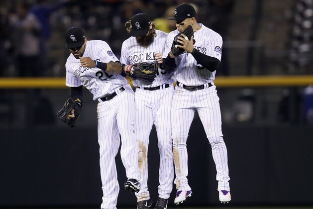 Colorado Rockies left fielder Ian Desmond, center fielder Charlie Blackmon and right fielder Carlos Gonzalez, from left, celebrate the team's 6-0 win over the Miami Marlins in a baseball game Tuesday, Sept. 27, 2017, in Denver. (AP Photo/David Zalubowski)