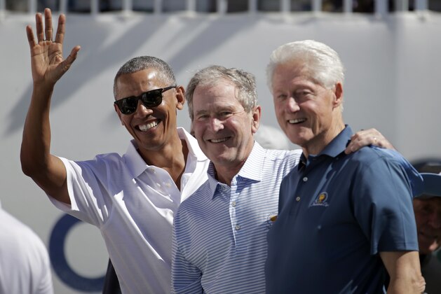 Former U.S. Presidents, from left, Barack Obama, George Bush and Bill Clinton greet spectators on the first tee before the first round of the Presidents Cup at Liberty National Golf Club in Jersey City, N.J., Thursday, Sept. 28, 2017. (AP Photo/Julio Cortez)