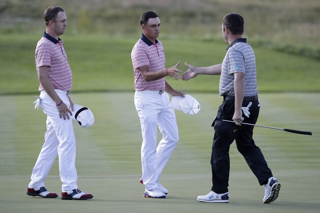 Louis Oosthuizen, right, greets Rickie Fowler, center, and Justin Thomas on the 16th green during the four-ball golf matches on the second day of the Presidents Cup at Liberty National Golf Club in Jersey City, N.J., Friday, Sept. 29, 2017. Fowler and Thomas won their match against Oosthuizen and Branden Grace. (AP Photo/Julio Cortez)