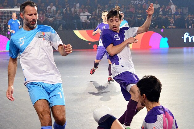 Former Manchester United footballer Ryan Giggs (L) is tackled while taking part in the final of the Indian Premier Futsal Football League match at The Peddem Indoor Stadium in Mapusa on July 24, 2016. / AFP / STR        (Photo credit should read STR/AFP/Getty Images)