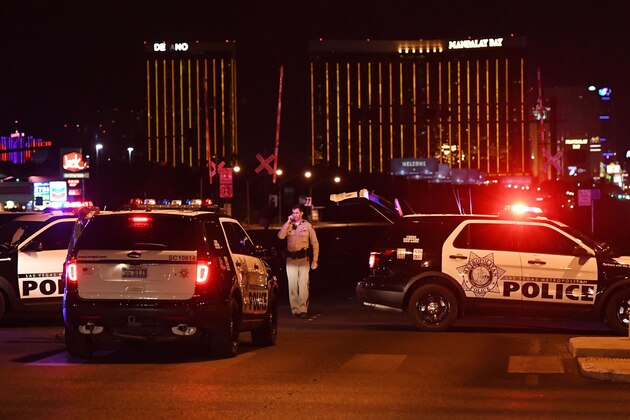 EDITORS NOTE: Graphic content / Police form a perimeter around the road leading to the Mandalay Hotel (background) after a gunman killed at least 50 people and wounded more than 200 others when he opened fire on a country music concert in Las Vegas, Nevada on October 2, 2017. 
Police said the gunman, a 64-year-old local resident named as Stephen Paddock, had been killed after a SWAT team responded to reports of multiple gunfire from the 32nd floor of the Mandalay Bay, a hotel-casino next to the concert venue. / AFP PHOTO / Mark RALSTON        (Photo credit should read MARK RALSTON/AFP/Getty Images)