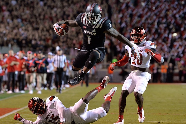 RALEIGH, NC - OCTOBER 05:  Jaylen Samuels #1 of the North Carolina State Wolfpack hurdles Trumaine Washington #15 of the Louisville Cardinals during the game at Carter Finley Stadium on October 5, 2017 in Raleigh, North Carolina.  (Photo by Grant Halverson/Getty Images)