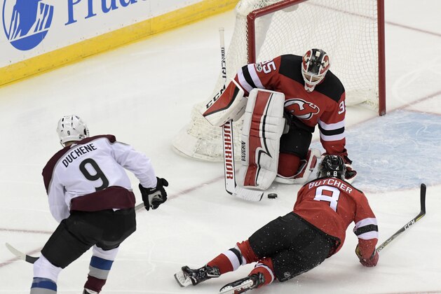 New Jersey Devils goalie Cory Schneider (35) stops the puck as Colorado Avalanche center Matt Duchene (9) and Devils defenseman Will Butcher (8) look on during the third period of an NHL hockey game Saturday, Oct. 7, 2017, in Newark, N.J. The Devils won 4-1. (AP Photo/Bill Kostroun)