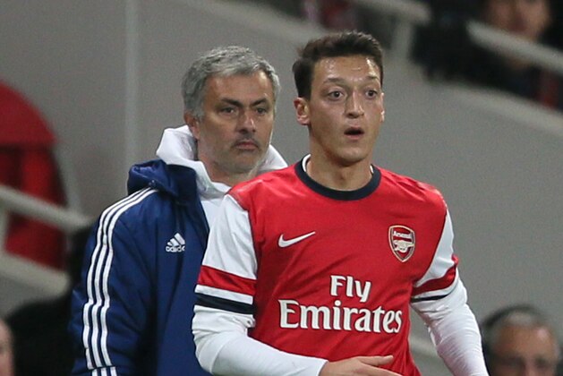 Chelsea's manager Jose Mourinho, left looks on as Arsenal's Mesut Ozil watches the ball following a throw in during their English League Cup soccer match between Arsenal and Chelsea at the Emirates stadium in London Tuesday, Oct. 29, 2013. (AP Photo/Alastair Grant)