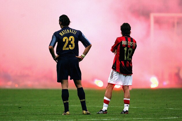 MILAN, ITALY -  APRIL 12:  Marco Materazzi of Inter Milan and Rui Costa of AC Milan look on as Inter fans shower the pitch with flares during the UEFA Champions League quarter-final second leg between AC Milan and Inter Milan at the San Siro Stadium on April 12, 2005  in Milan, Italy. (Photo by Mike Hewitt/Getty Images)