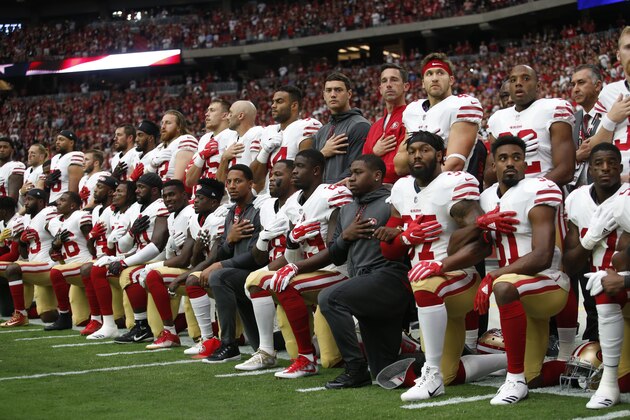 PHOENIX, AZ - OCTOBER 1: The San Francisco 49ers kneel and stand in solidarity on the sideline, during the anthem, prior to the game against the Arizona Cardinals at the University of Phoenix Stadium on October 1, 2017 in Phoenix, Arizona. The Cardinals defeated the 49ers 18-15. (Photo by Michael Zagaris/San Francisco 49ers/Getty Images)  *** Local Caption ***