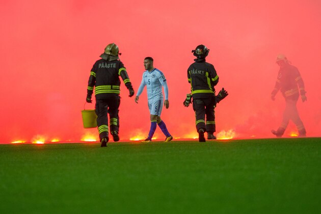 Firemen run on the pitch to take care of flares thrown by Bosnia fans during the FIFA World Cup 2018 qualification football match between Estonia and Bosnia in Tallinn, Estonia on October 10, 2017. / AFP PHOTO / RAIGO PAJULA        (Photo credit should read RAIGO PAJULA/AFP/Getty Images)