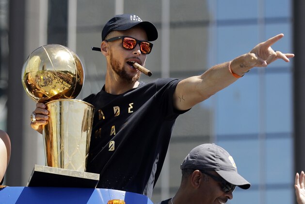 FILE - In this June 15, 2017, file photo, Golden State Warriors' Stephen Curry waves at fans during a parade and rally in Oakland, Calif., celebrating the team's the NBA basketball championship. One of the NBA's biggest bargains until now, Curry is about to receive his massive payday.  Golden State general manager Bob Myers said Friday, June 30, 2017, the Warriors will finalize a contract with the two-time MVP once the free agency moratorium ends July 6.  (AP Photo/Marcio Jose Sanchez, File)