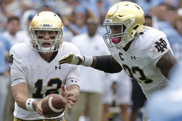 Notre Dame quarterback Ian Book, left, hands off to Josh Adams (33) during the first half of an NCAA college football game against North Carolina in Chapel Hill, N.C., Saturday, Oct. 7, 2017. (AP Photo/Gerry Broome)