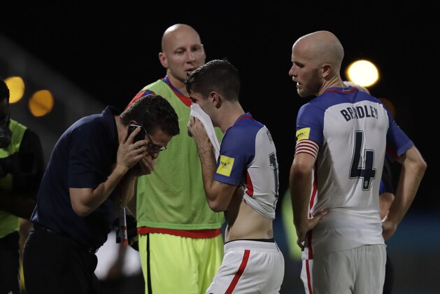 United States' Christian Pulisic, center, and his teammate United States' Michael Bradley, right, walk on the pitch after losing 2-1 against Trinidad and Tobago during a 2018 World Cup qualifying soccer match  in Couva, Trinidad, Tuesday, Oct. 10, 2017. (AP Photo/Rebecca Blackwell)