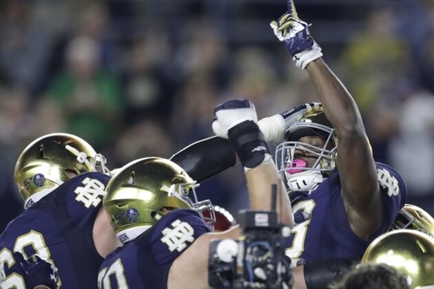 Notre Dame running back Josh Adams points skyward while lifted by teammates after one of his three touchdowns in an NCAA college football game against Southern California, Saturday, Oct. 21, 2017, in South Bend, Ind. (AP Photo/Carlos Osorio)