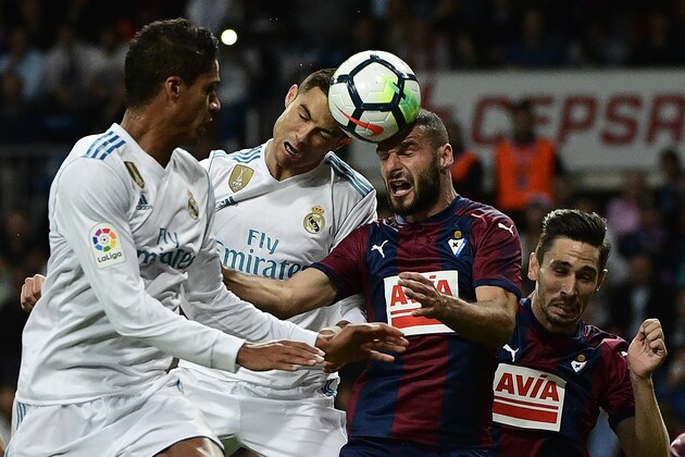 Real Madrid's Portuguese forward Cristiano Ronaldo (2nd-L) heads the ball with Eibar's Spanish defender David Lomban next to Real Madrid's French defender Raphael Varane (L) and Eibar's Portuguese defender Paulo Rodrigues Oliveira (R) during the Spanish league football match Real Madrid CF vs SD Eibar at the Santiago Bernabeu stadium in Madrid on October 22, 2017. / AFP PHOTO / PIERRE-PHILIPPE MARCOU        (Photo credit should read PIERRE-PHILIPPE MARCOU/AFP/Getty Images)