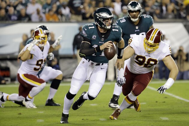Philadelphia Eagles quarterback Carson Wentz (11) scrambles as Washington Redskins defensive tackle Matthew Ioannidis (98) chases him during the first half of an NFL football game, Monday, Oct. 23, 2017, in Philadelphia. (AP Photo/Michael Perez)