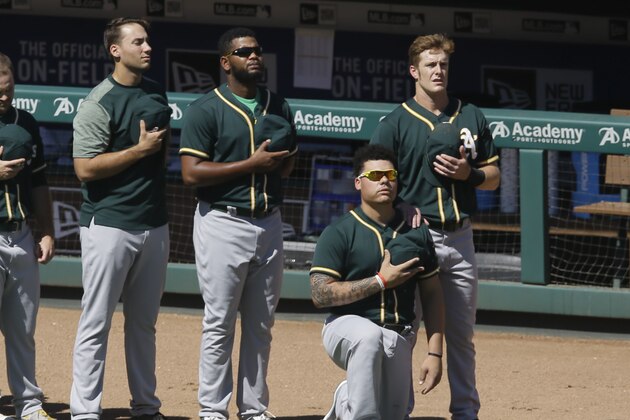 Oakland Athletics catcher Bruce Maxwell takes a knee next to teammate Mark Canha, right, during the national anthem before a baseball game against the Texas Rangers in Arlington, Texas, Sunday, Oct. 1, 2017. (AP Photo/LM Otero)